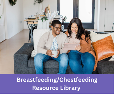 a smiling couple sits on a couch looking at a tablet