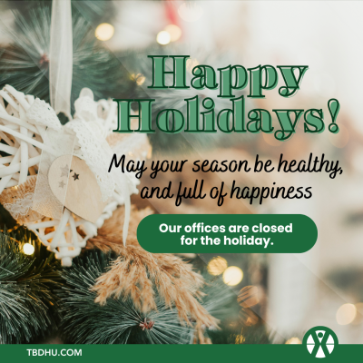 A happy holidays message displays in front of an ornamental evergreen tree